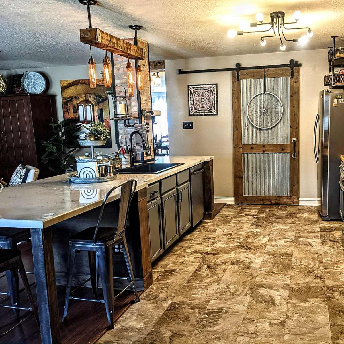 A modern kitchen with a large island, stainless steel appliances, a sliding barn door, and a mix of open and closed cabinetry.