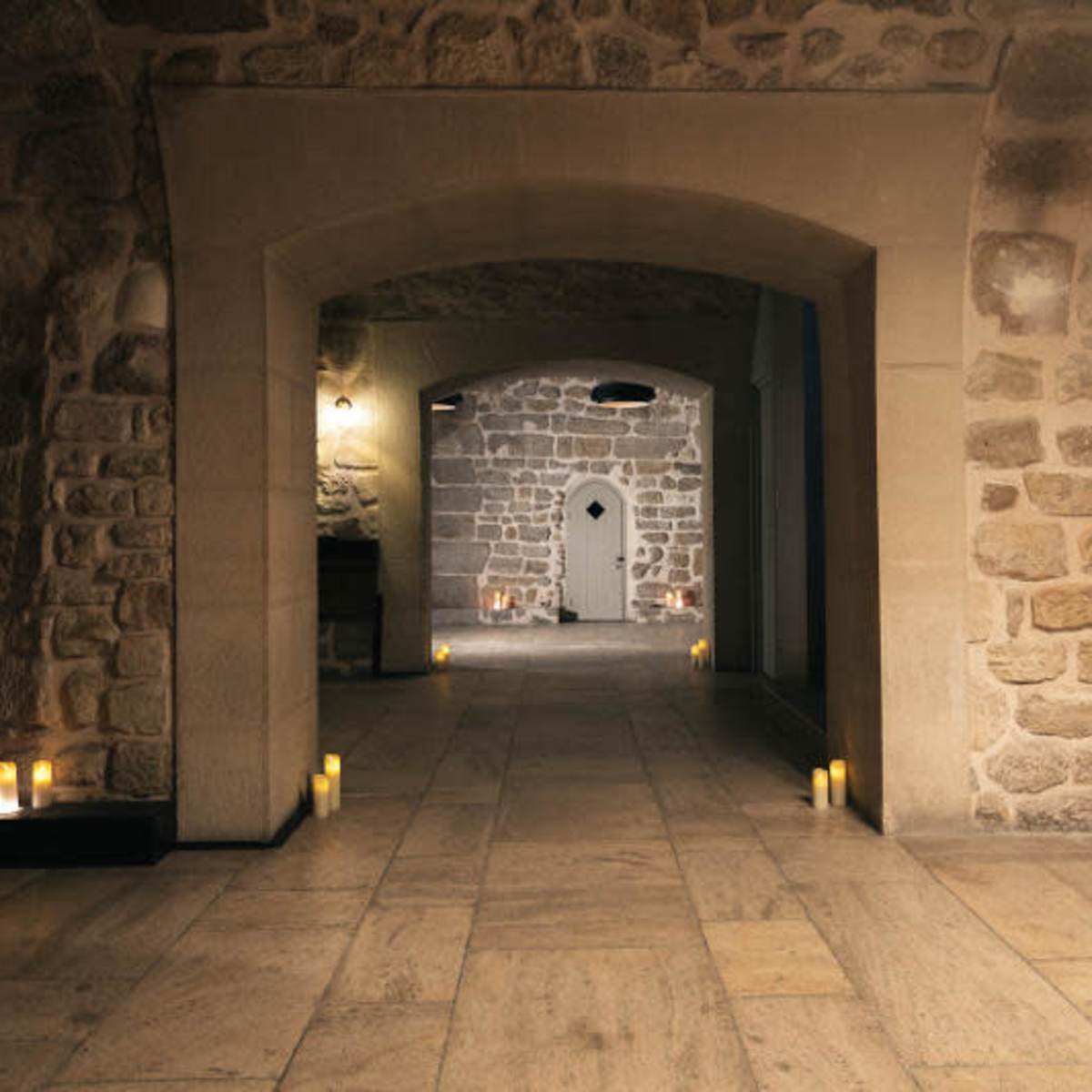 A stone-walled interior features arched doorways and candle-lit spaces.