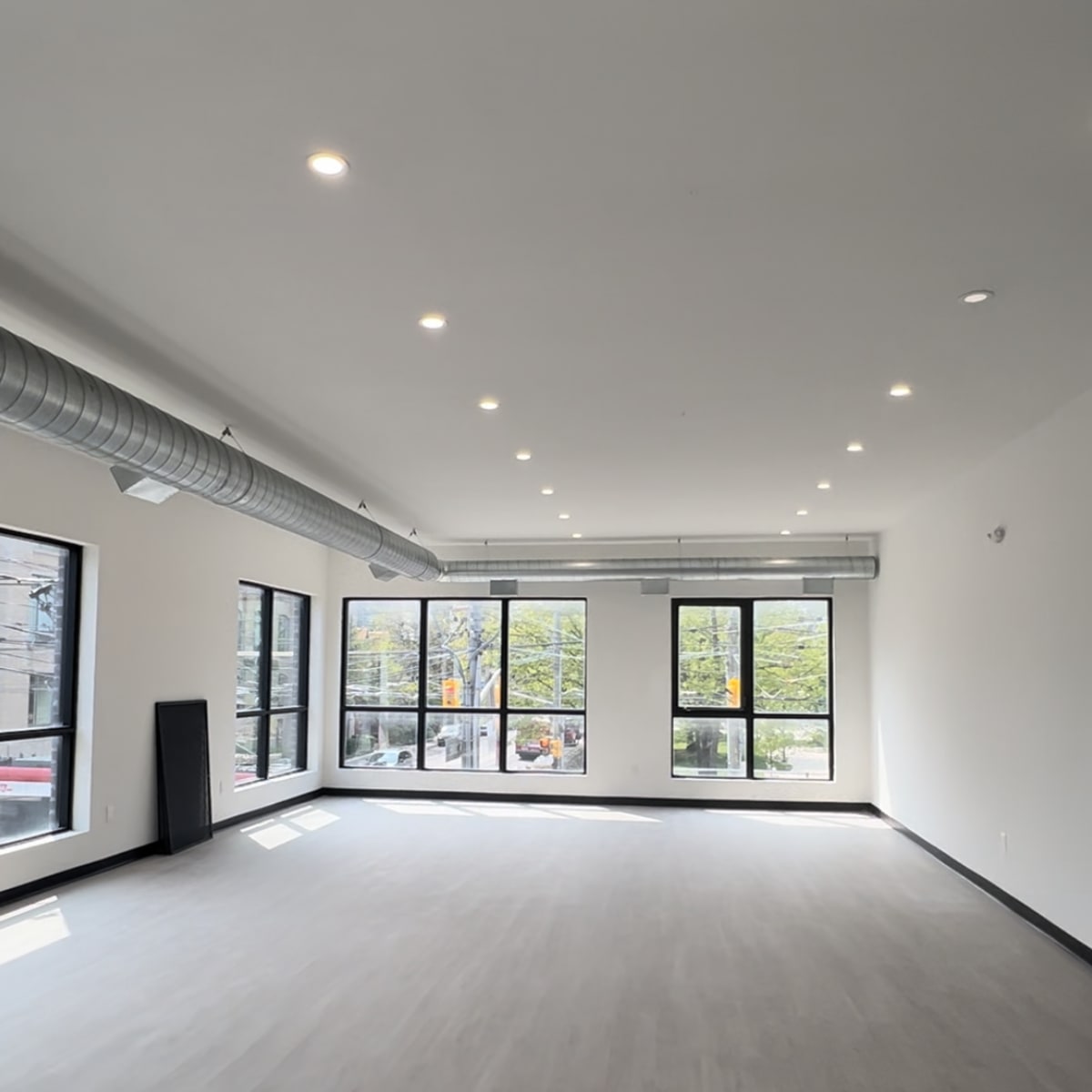 A spacious, empty room with large windows and a polished grey floor.
