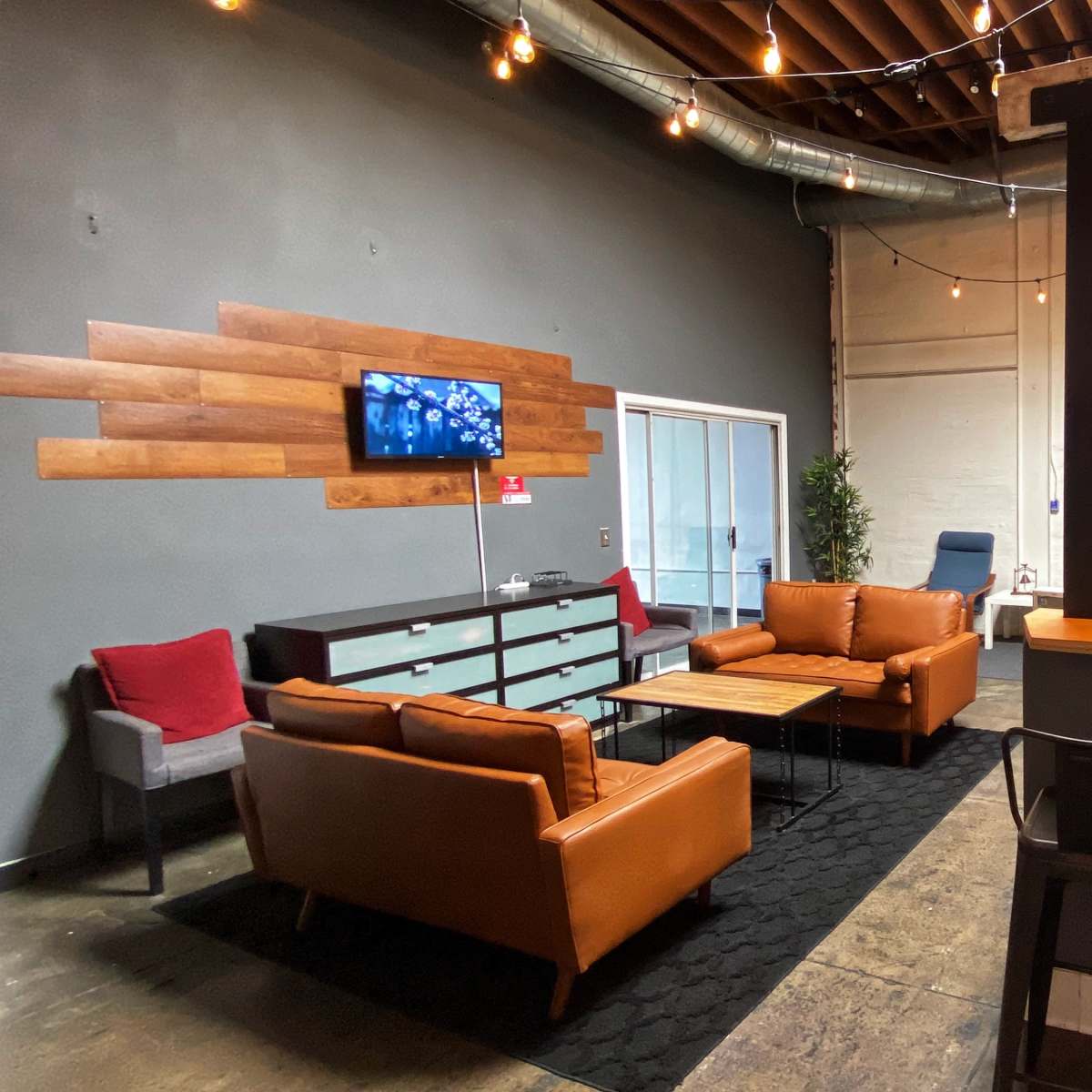A modern lounge area features brown leather sofas, a wooden coffee table, and a kitchenette with bar seating.