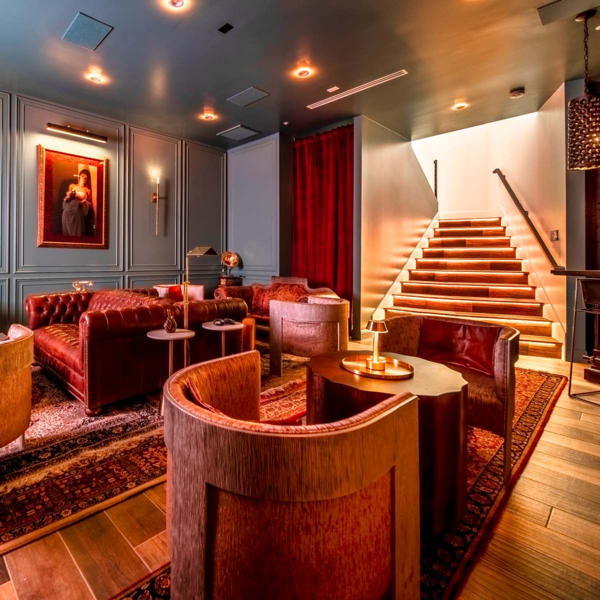 A stylish lounge area with leather seating, decorative artwork on the walls, and a staircase leading to a different level.