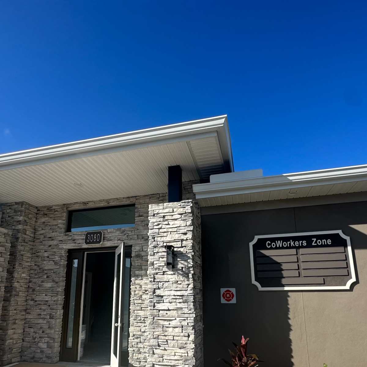 A modern building with stone accents and a sign that reads "CoWorkers Zone" on the side.