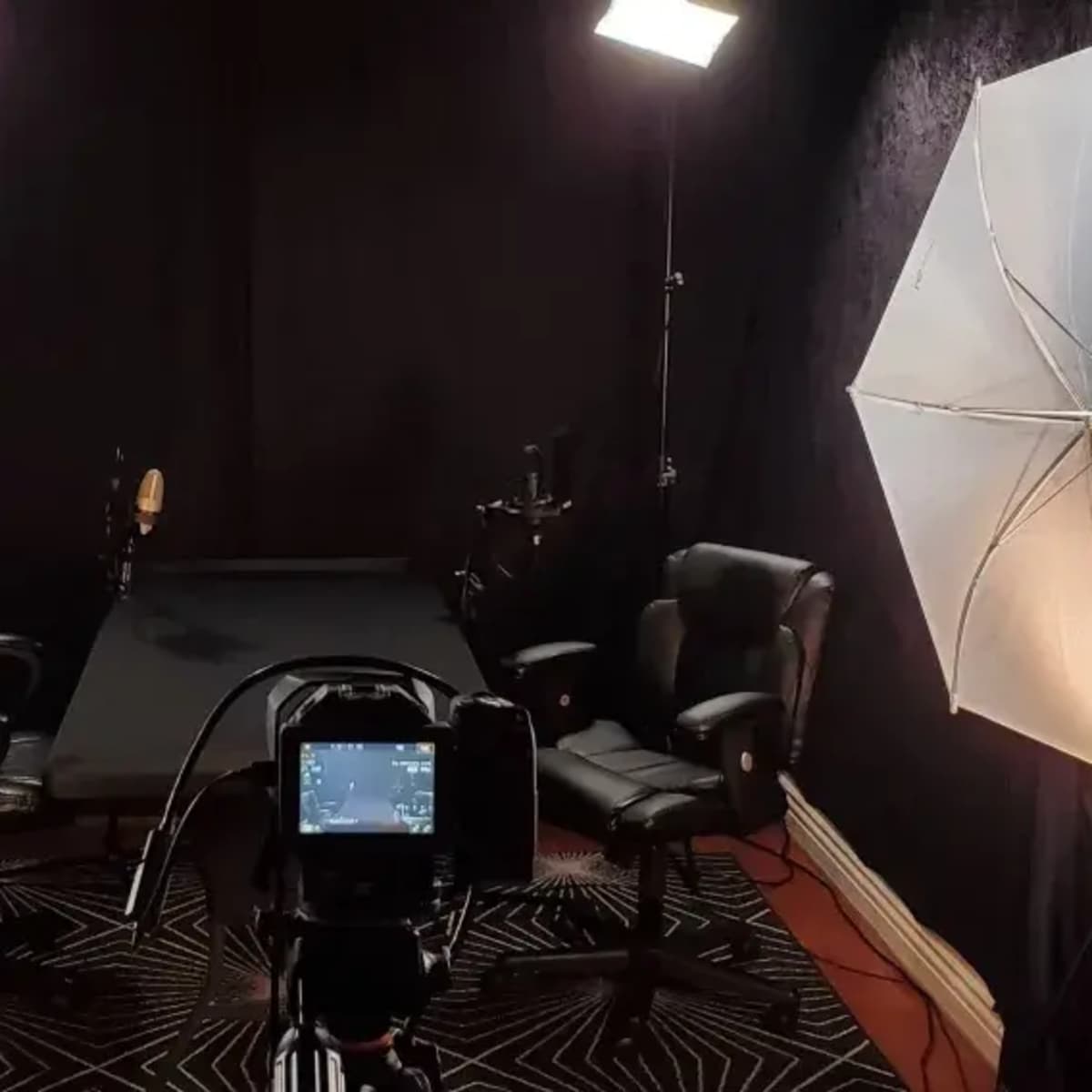 A photography studio setup with two chairs, a central table, and lighting equipment arranged on either side.