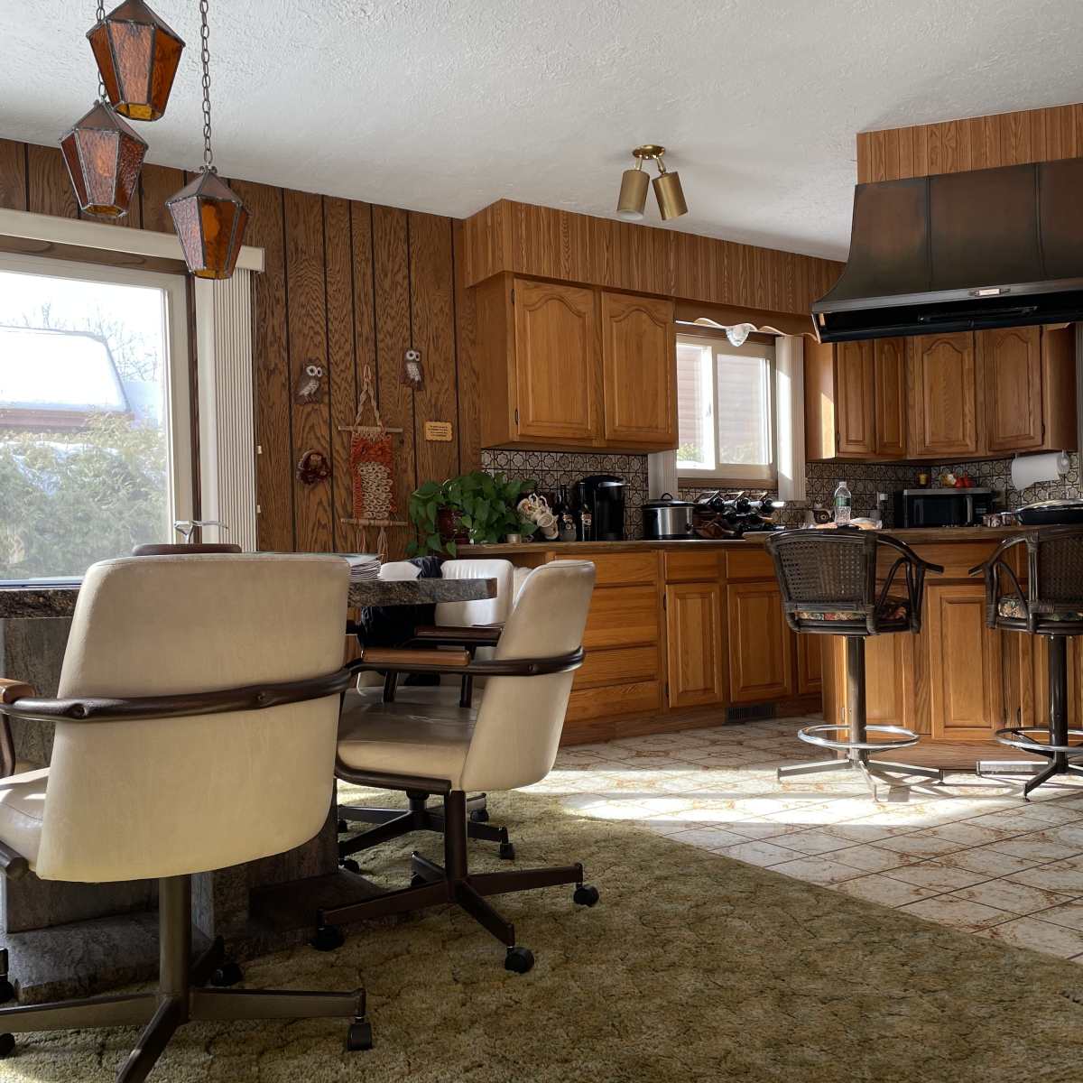 A spacious kitchen with wooden cabinetry, a large countertop, and a dining area featuring two upholstered chairs.
