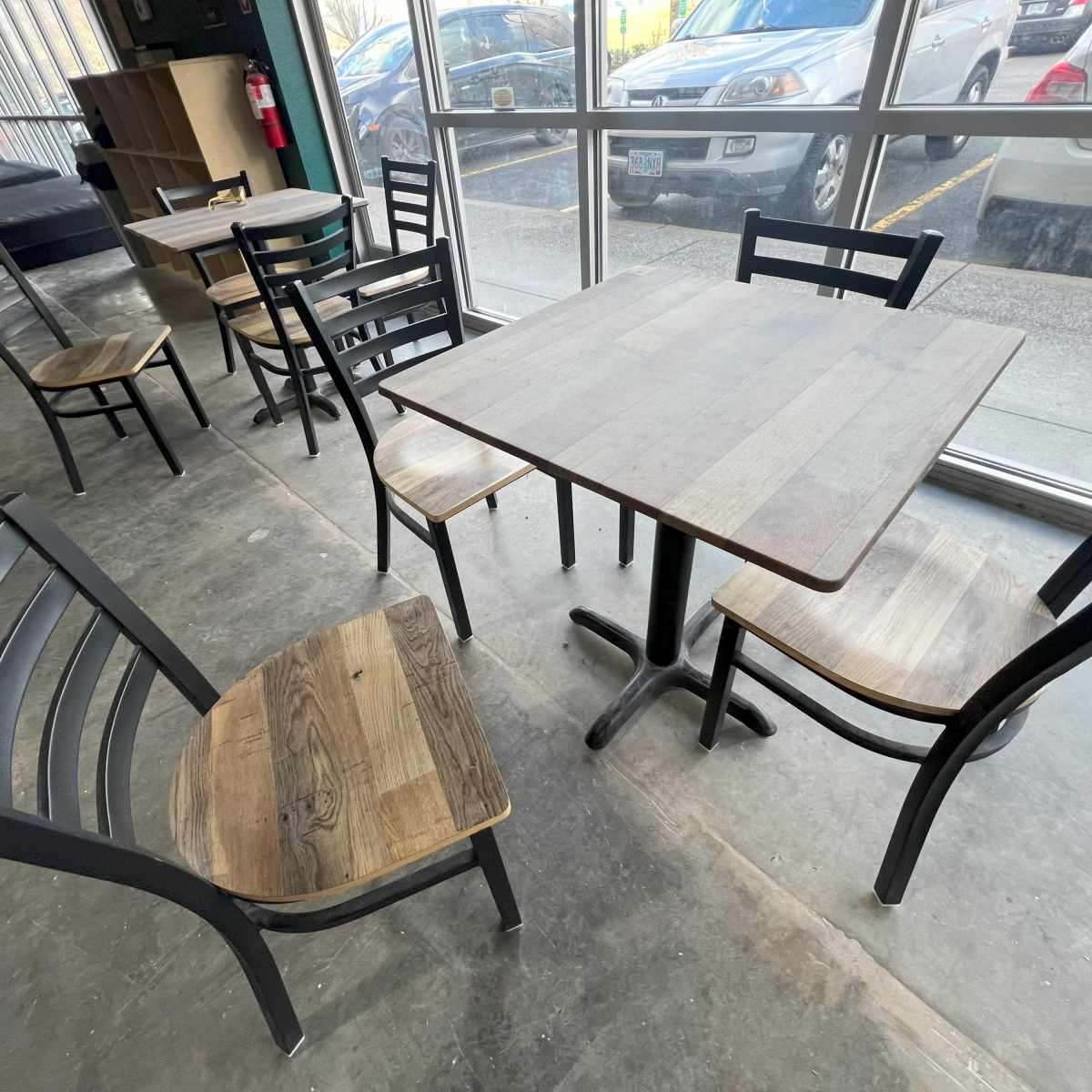 A wooden table surrounded by several metal and wooden chairs is situated in a well-lit interior space.