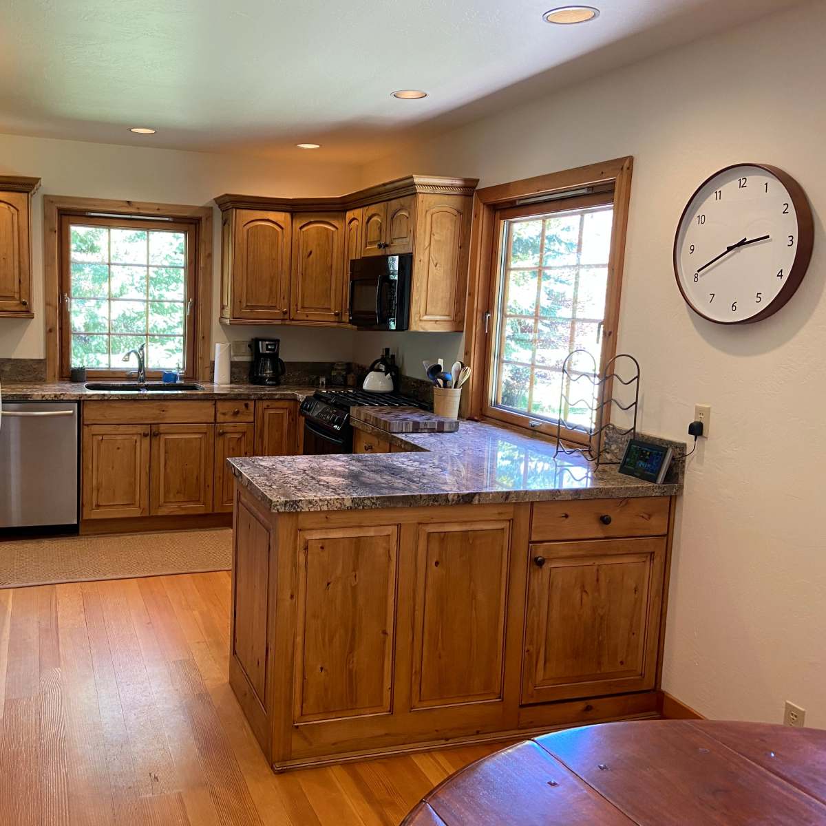 The kitchen features wooden cabinetry, a granite countertop island, and stainless steel appliances.