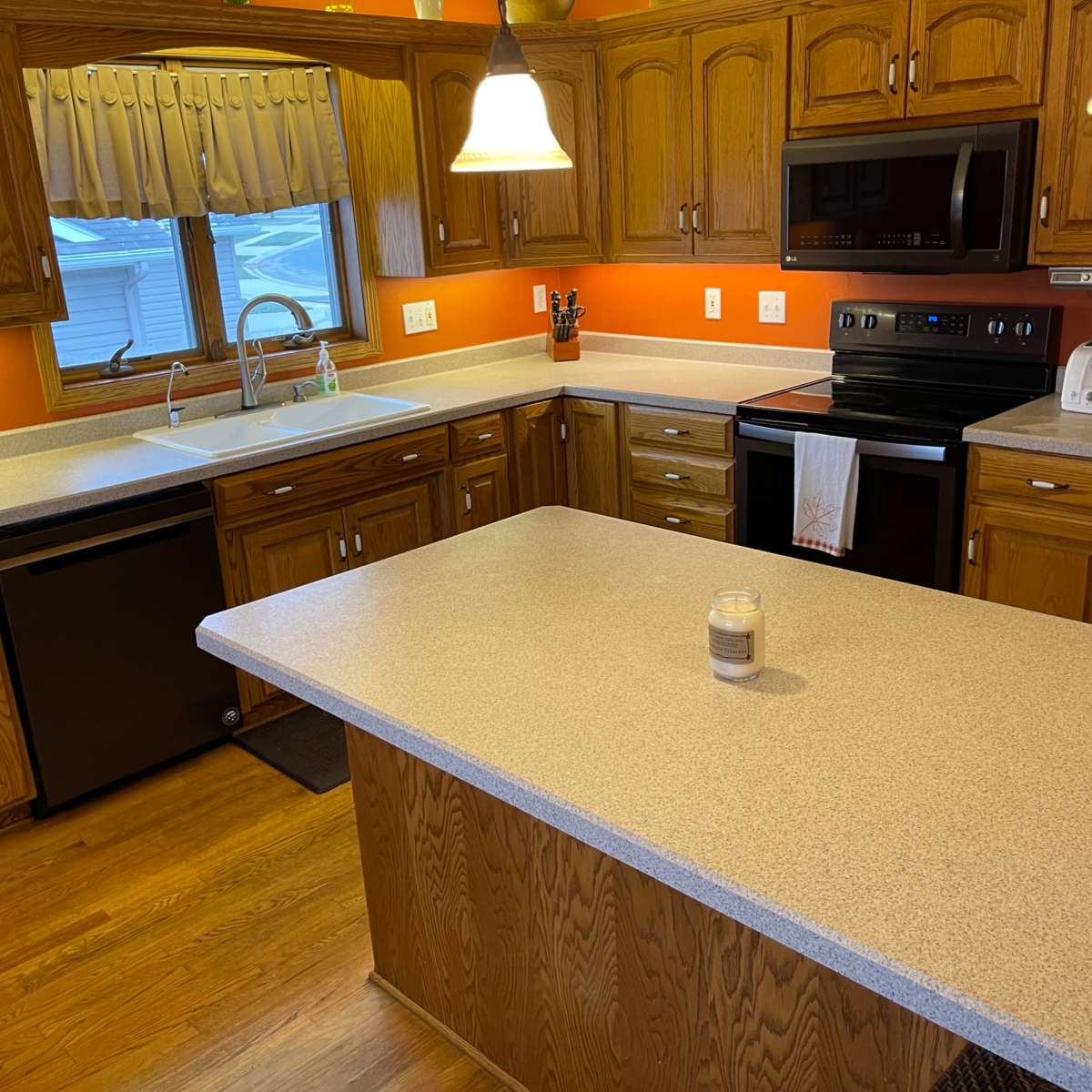 The kitchen features wooden cabinetry, a countertop island, and modern appliances, including a stove and dishwasher.