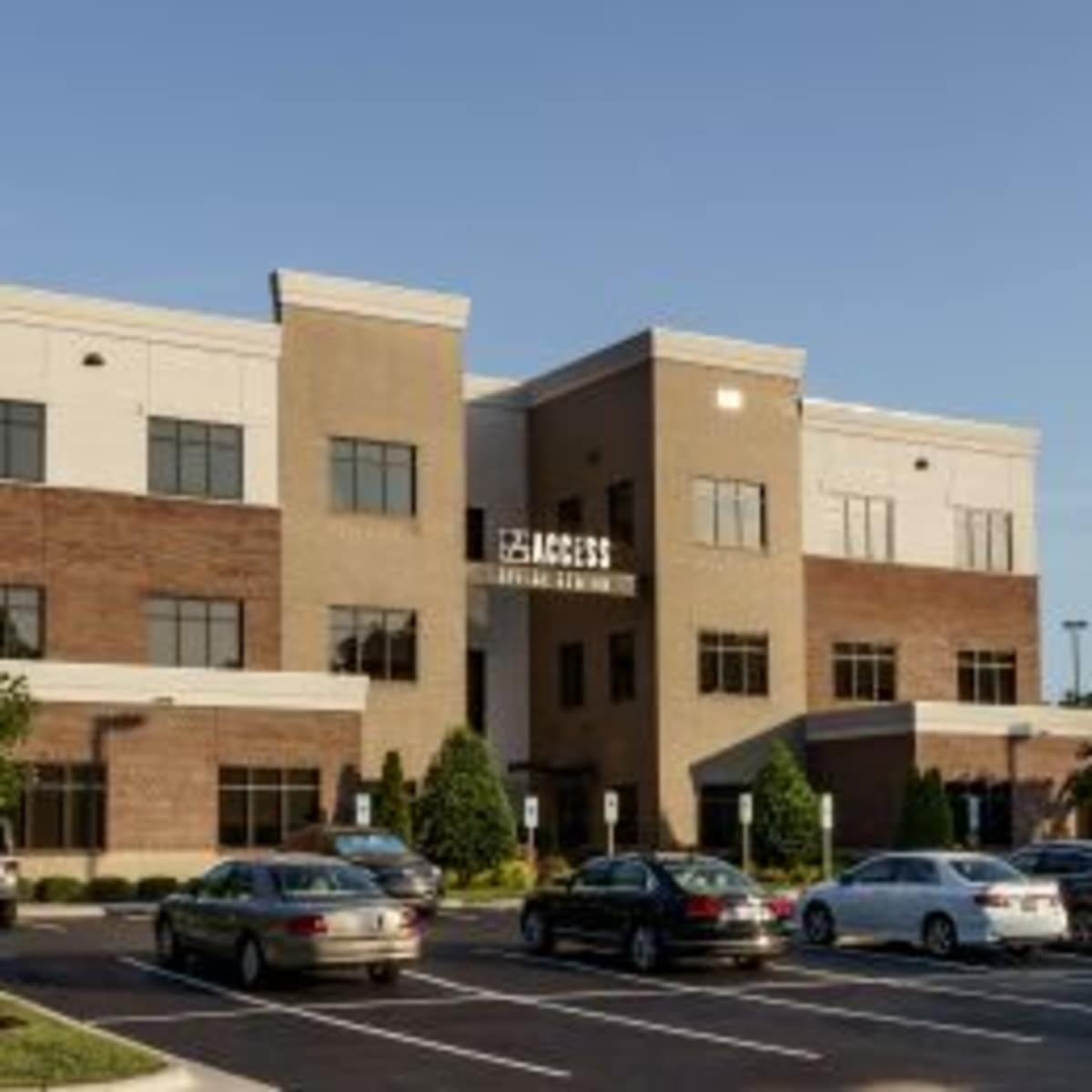 A multi-story commercial building with a brick and stucco exterior and a landscaped parking lot.