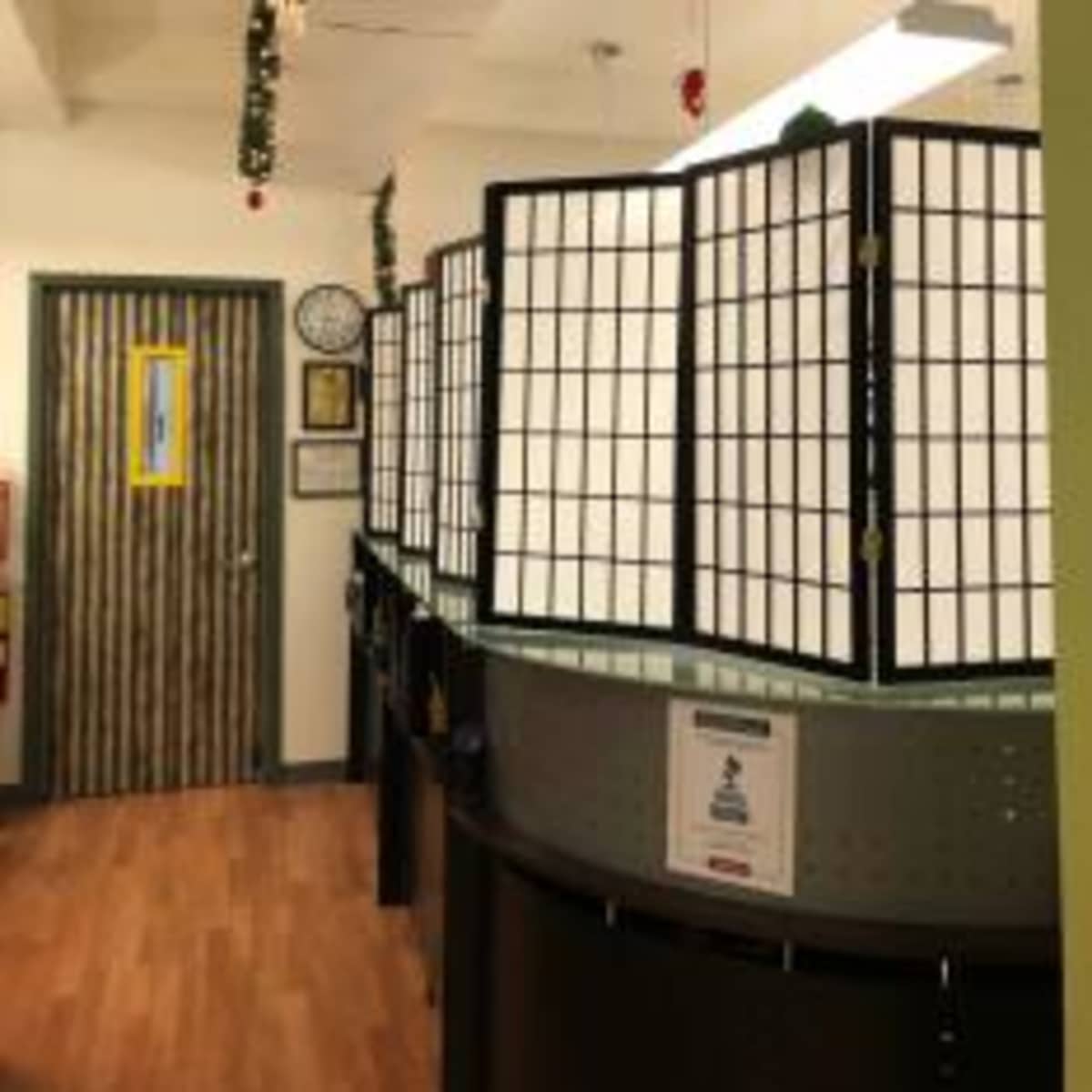 A hallway with a series of partition screens separating work areas, leading to a door at the end.