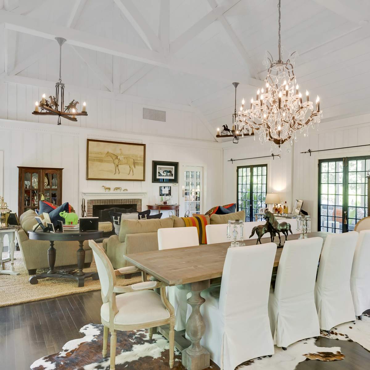 A spacious living and dining area featuring a chandelier, a large dining table, and a cozy seating arrangement with a fireplace.