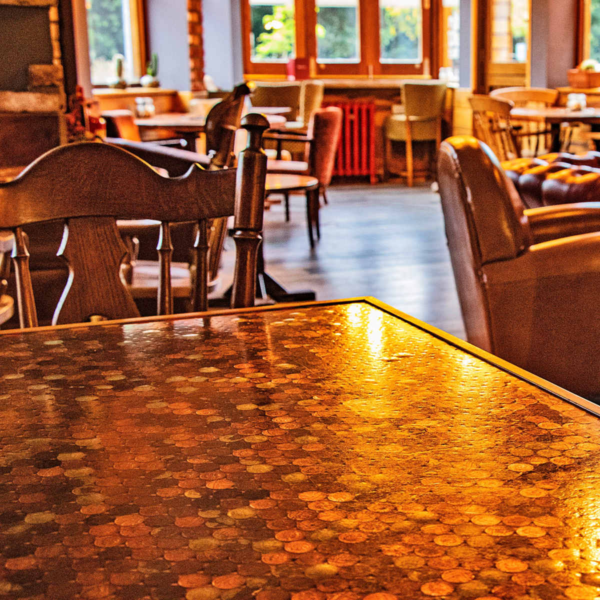 A cozy cafe interior with a table made of coins and various seating options in the background.