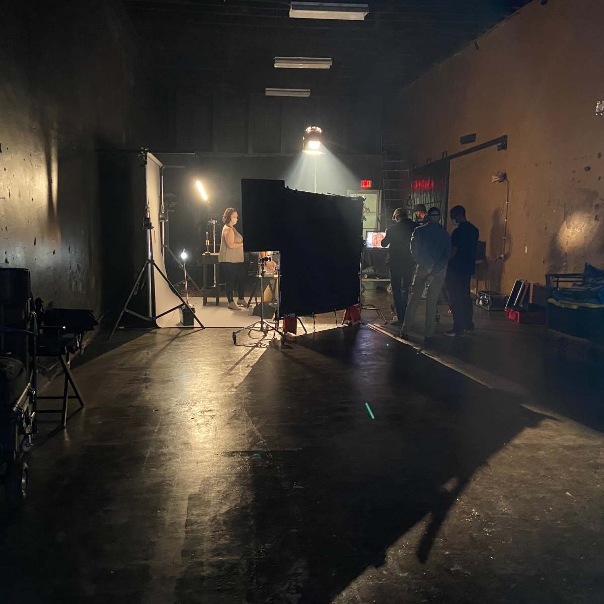 A film crew sets up equipment in a dimly lit studio for a recording session.