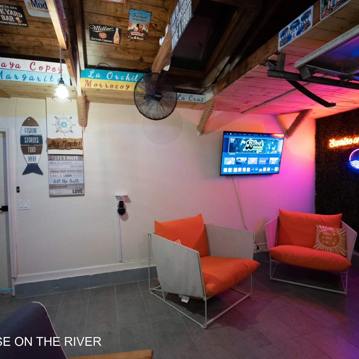 A cozy indoor space with a television, orange seating, and decorative signs on the walls.