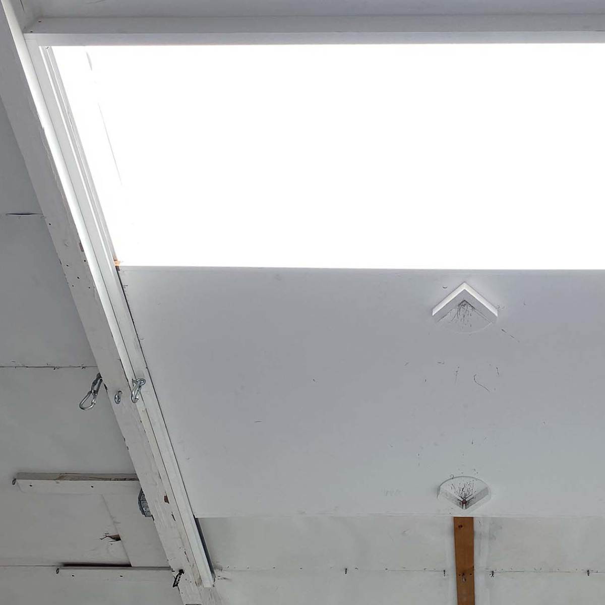 A bright skylight mounted in a white ceiling with visible structural elements.