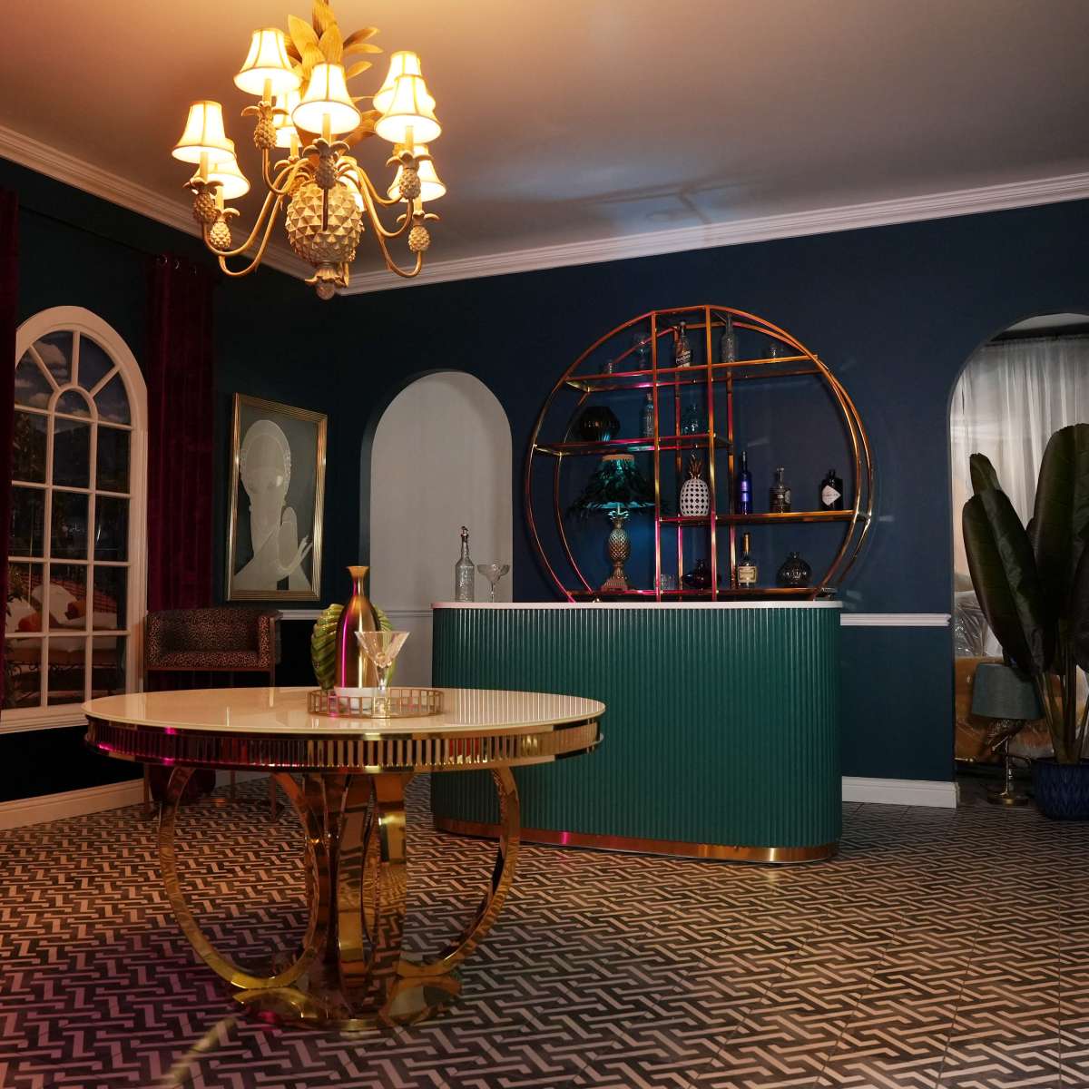 An elegantly styled interior featuring a green bar against a blue wall, a round dining table, and decorative lighting.