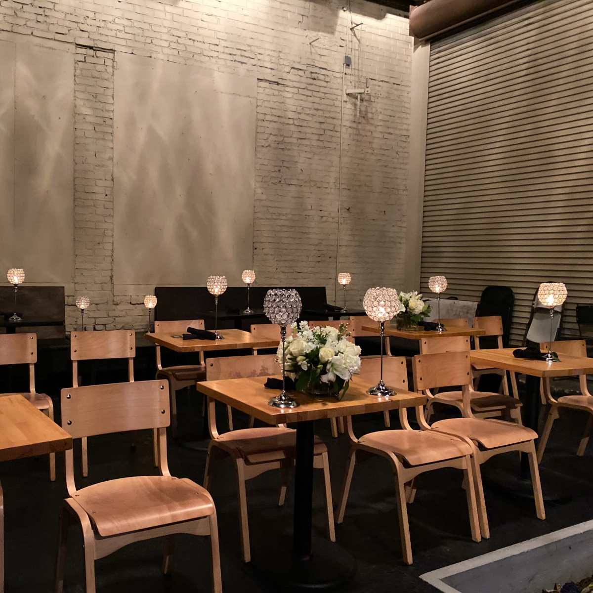 A dining area features rows of wooden tables and chairs, each adorned with a decorative lamp and a floral centerpiece.