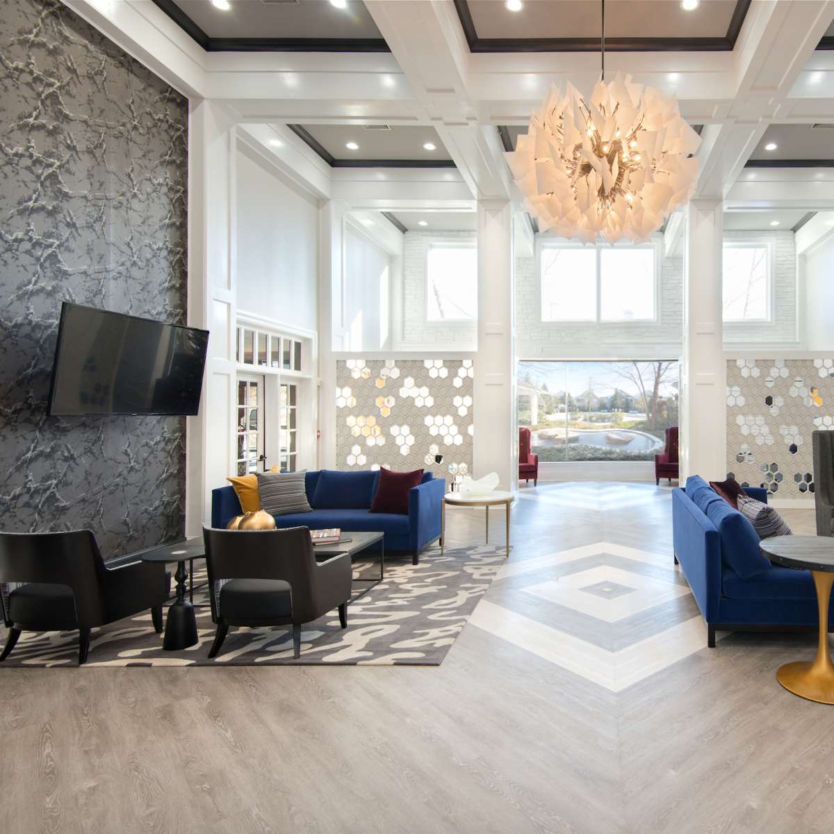 A modern lobby with a mix of seating arrangements, large windows, and decorative wall art.