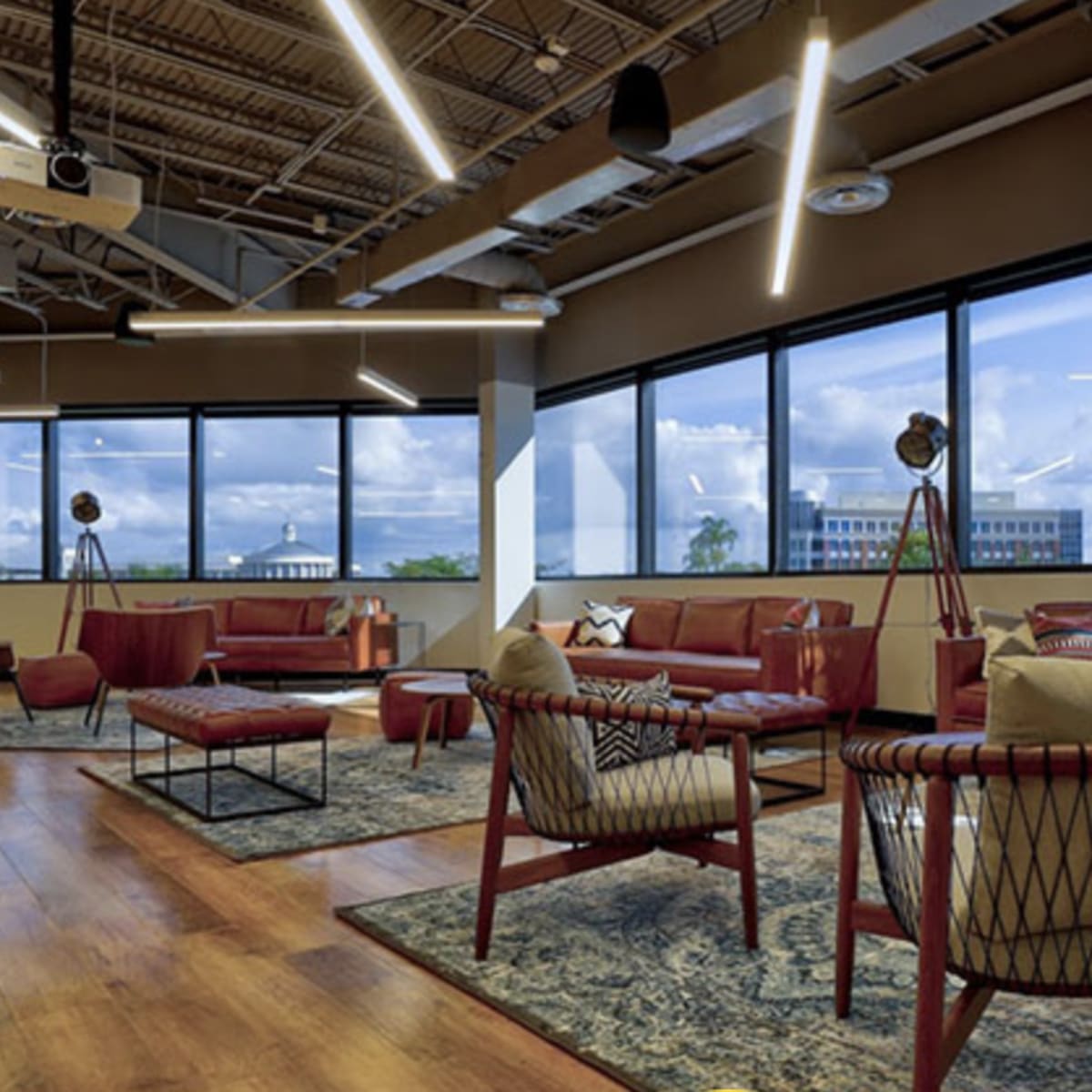 A modern lounge area with red seating, patterned rugs, and large windows that provide a view of the outdoors.