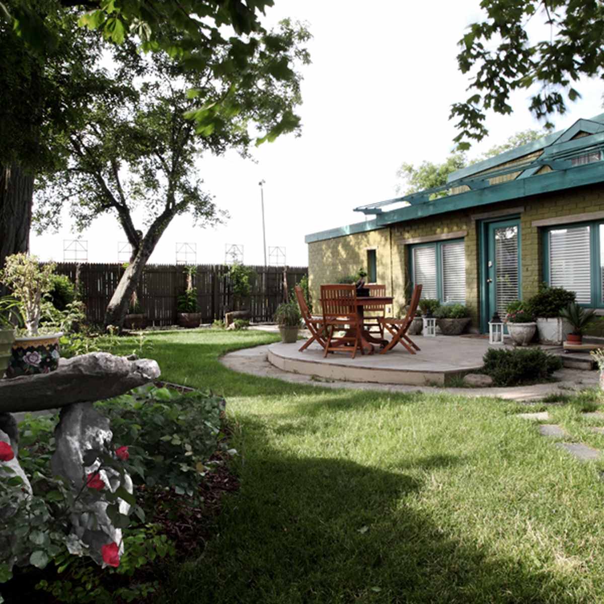 A well-maintained garden features a seating area surrounded by lush greenery and decorative planters.