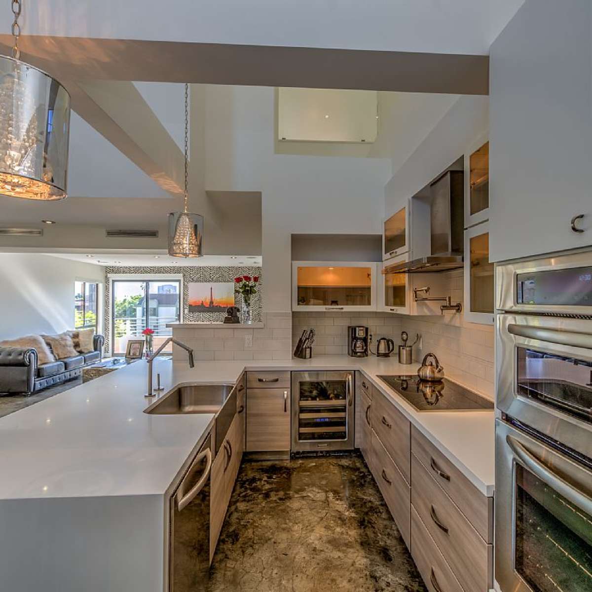 A modern kitchen with a large island featuring a sink, surrounded by sleek cabinetry and stainless steel appliances.