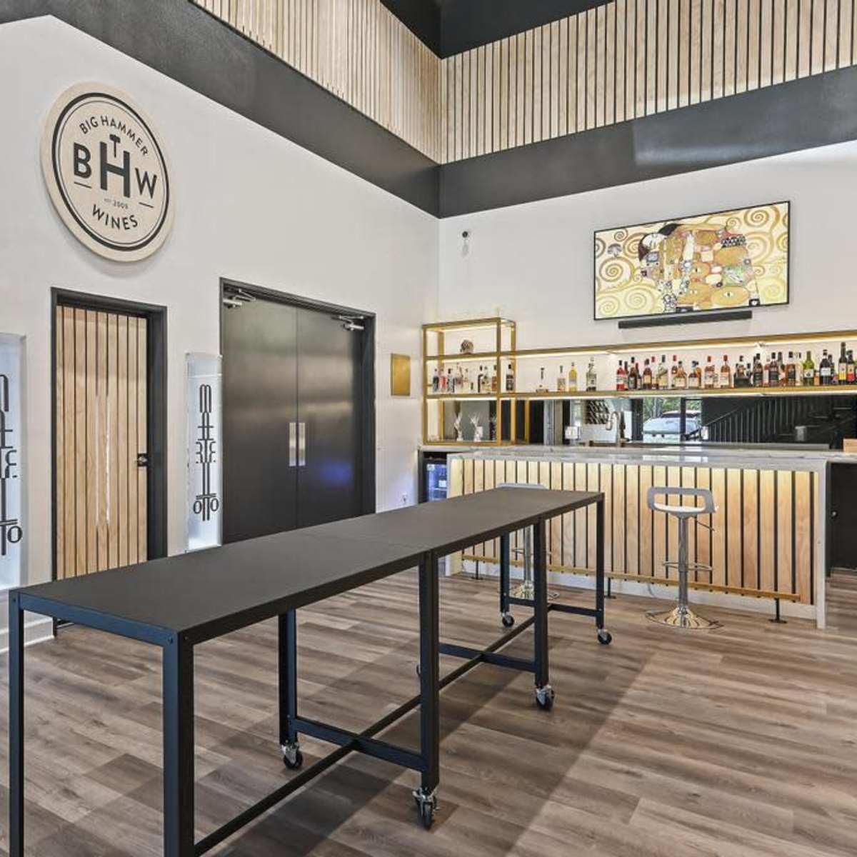 A modern wine tasting room with a sleek bar, wine racks on the wall, and contemporary decor.