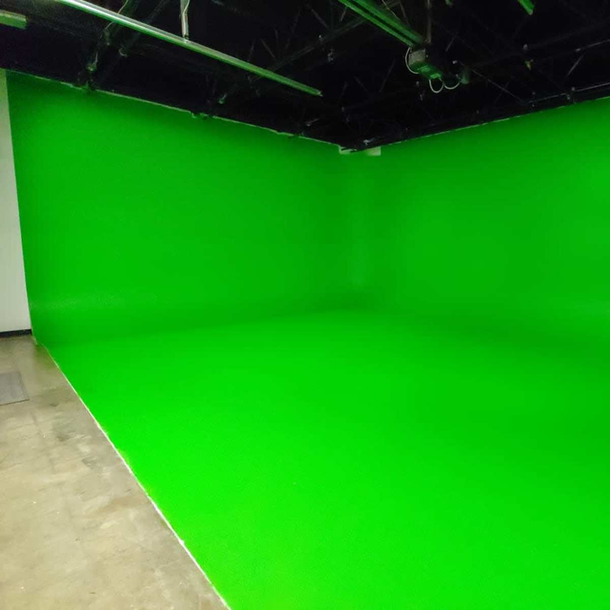 A studio space with a bright green backdrop and a smooth floor.