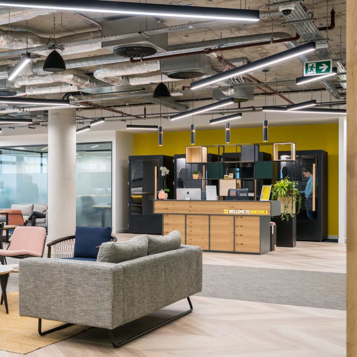 A modern office interior with seating areas, desks, and large windows allowing natural light.