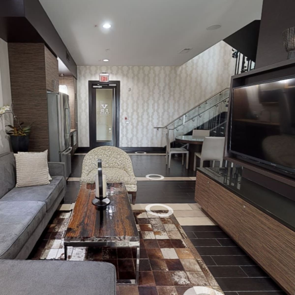 A modern living area with a gray sofa, a coffee table, and a large wall-mounted television.