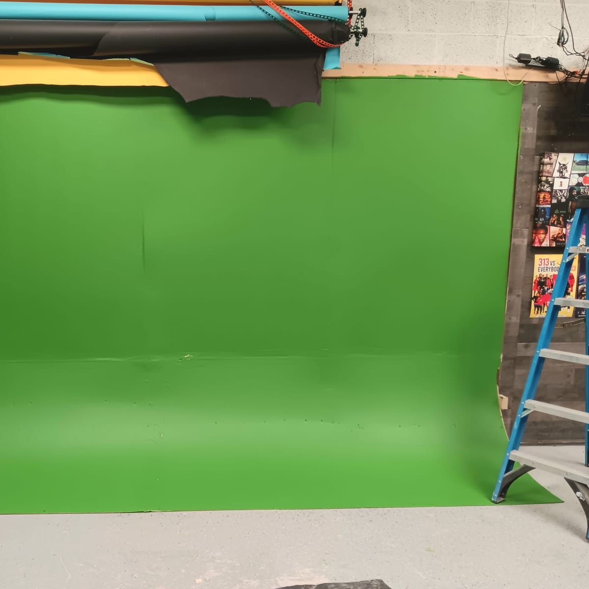 A green screen setup with various colored backdrops and a ladder in a studio environment.