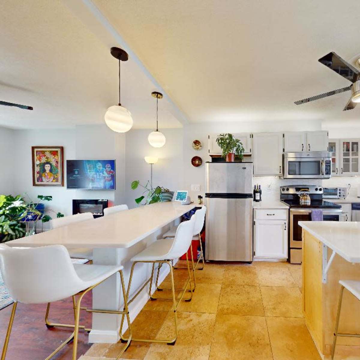 A modern kitchen and dining area featuring stainless steel appliances, white cabinetry, and a large island with seating.