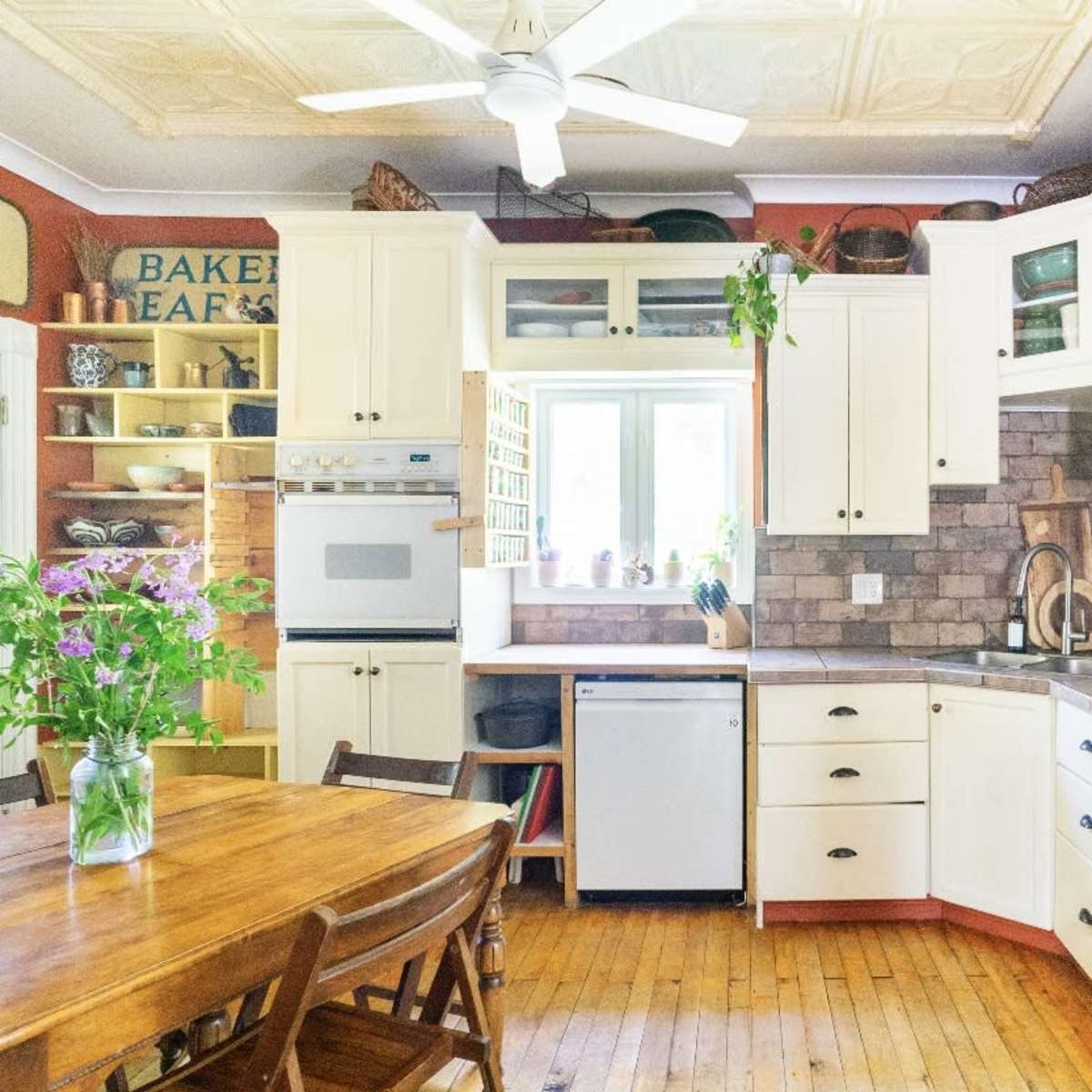 A well-organized kitchen featuring white cabinetry, a wooden table, and a variety of kitchen appliances.