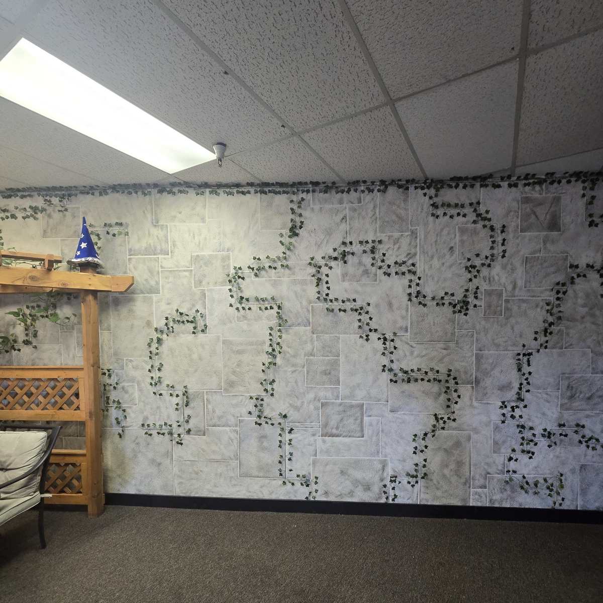 A room with a textured gray wall adorned with green vines and a wooden trellis on one side.