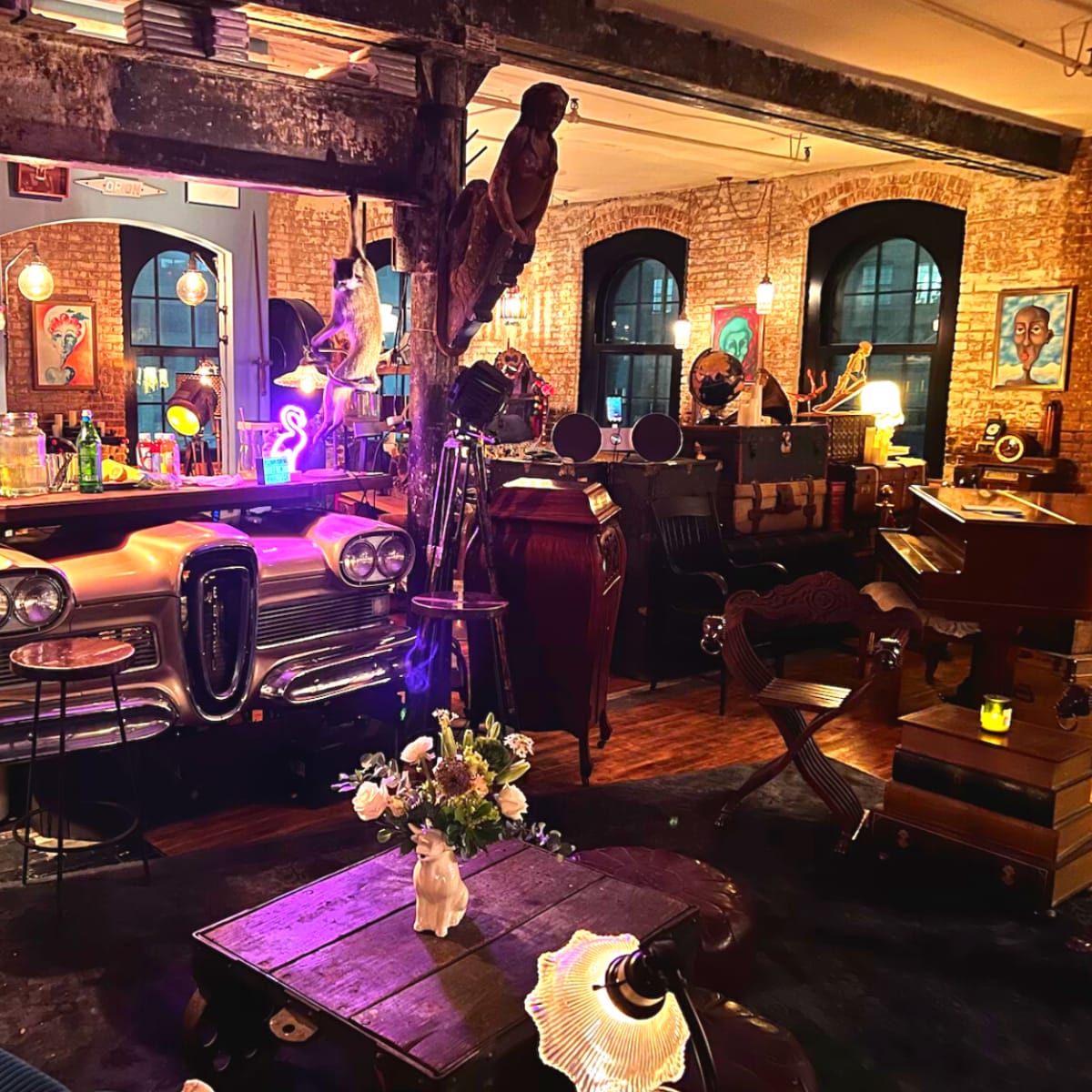 An eclectic interior scene with a vintage Edsel car serving as a bar, surrounded by various retro decor, plants, and furniture.