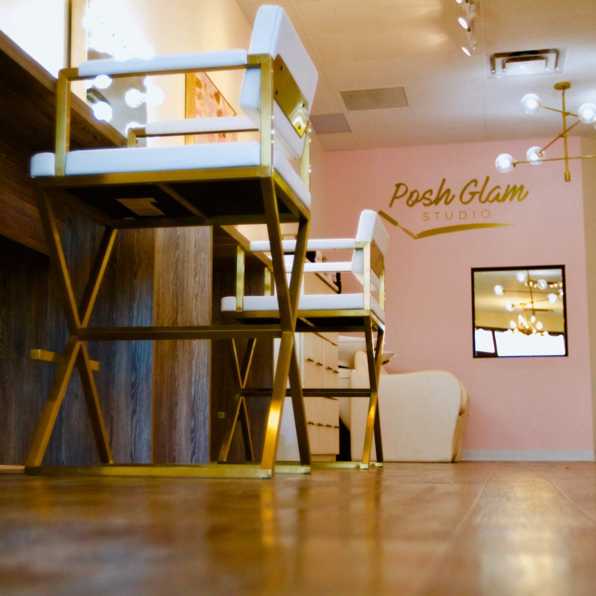 The interior of a beauty studio featuring modern furniture, including white and gold chairs and a wooden reception desk.