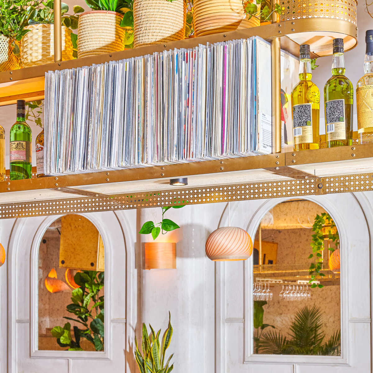 A restaurant interior featuring brown leather booths, a bar with various condiments, and shelves displaying wine bottles and vinyl records above.