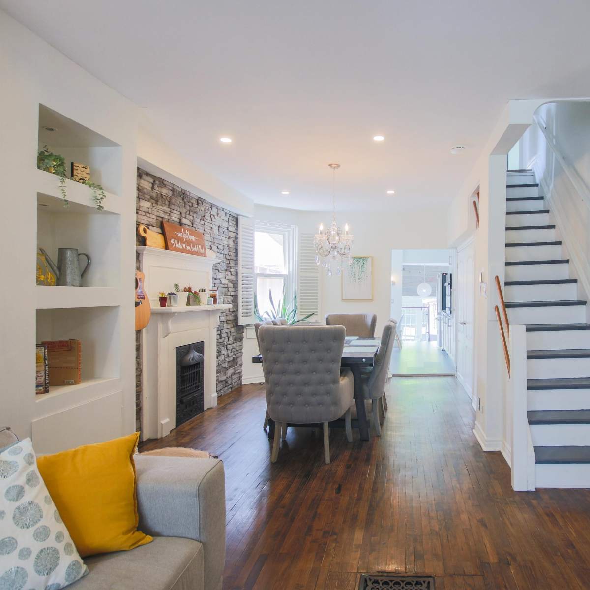 A well-lit open-concept living area with a staircase, dining table, and a fireplace.