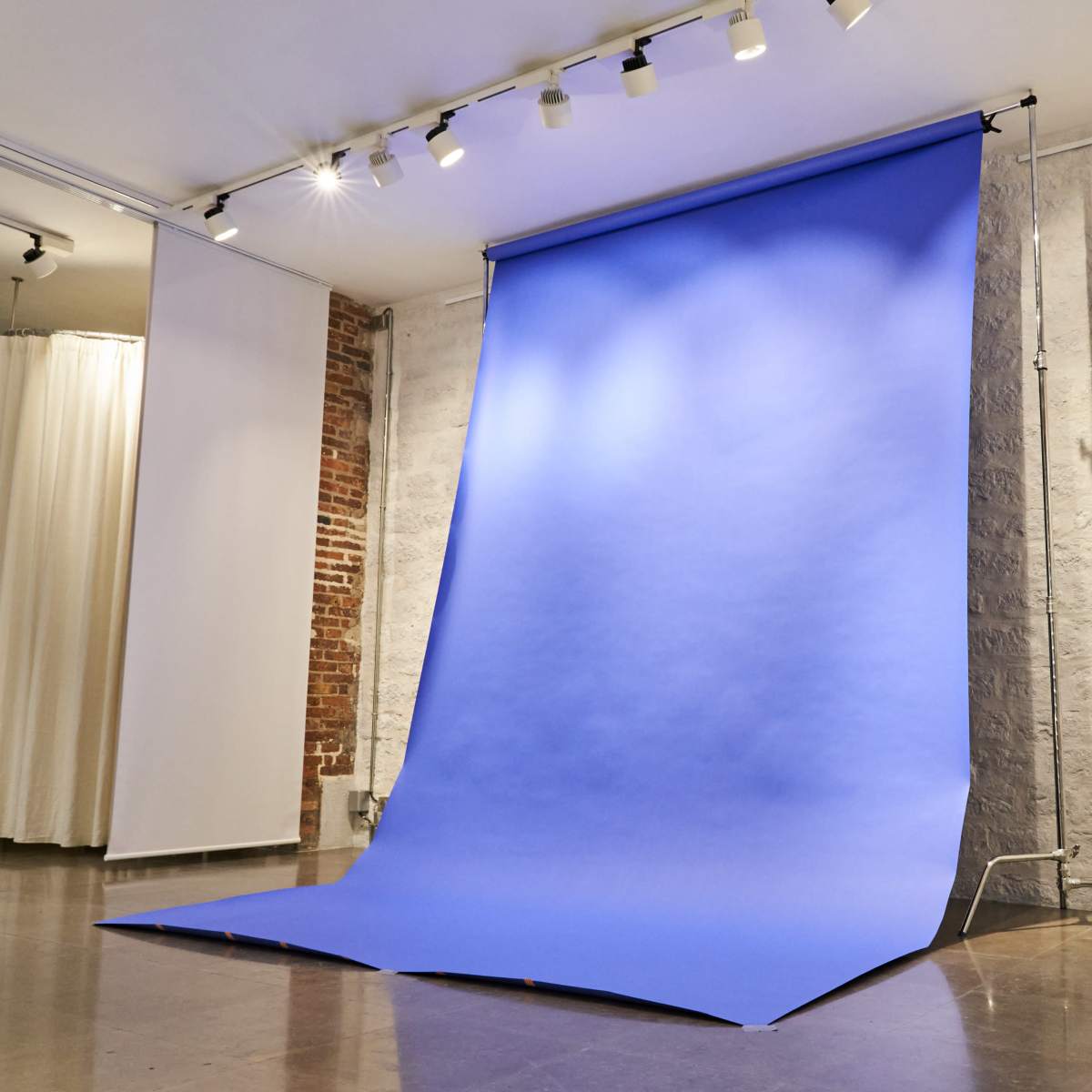 A photography studio with a large blue backdrop set up against a wall.