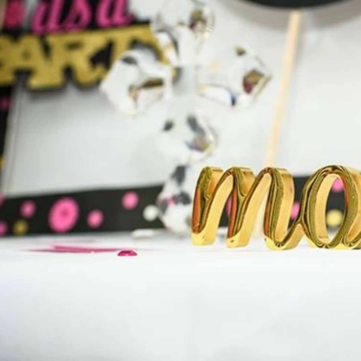 A gold decorative sign reading "mother" is placed on a table with party-themed decorations.