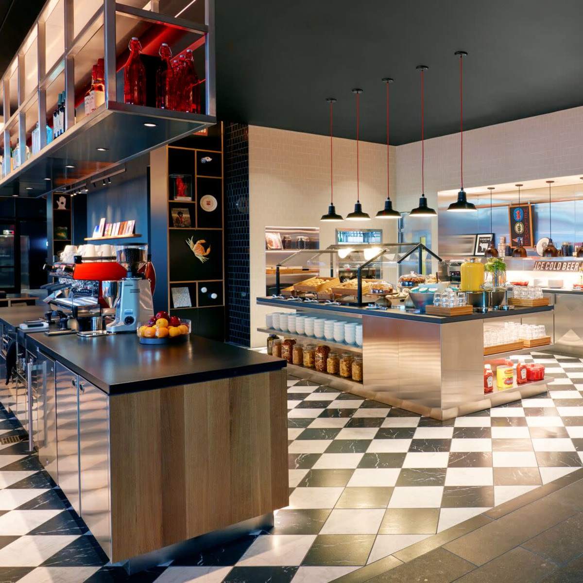 A modern café interior with a checkerboard floor, display shelves, and a counter featuring a variety of food and beverages.