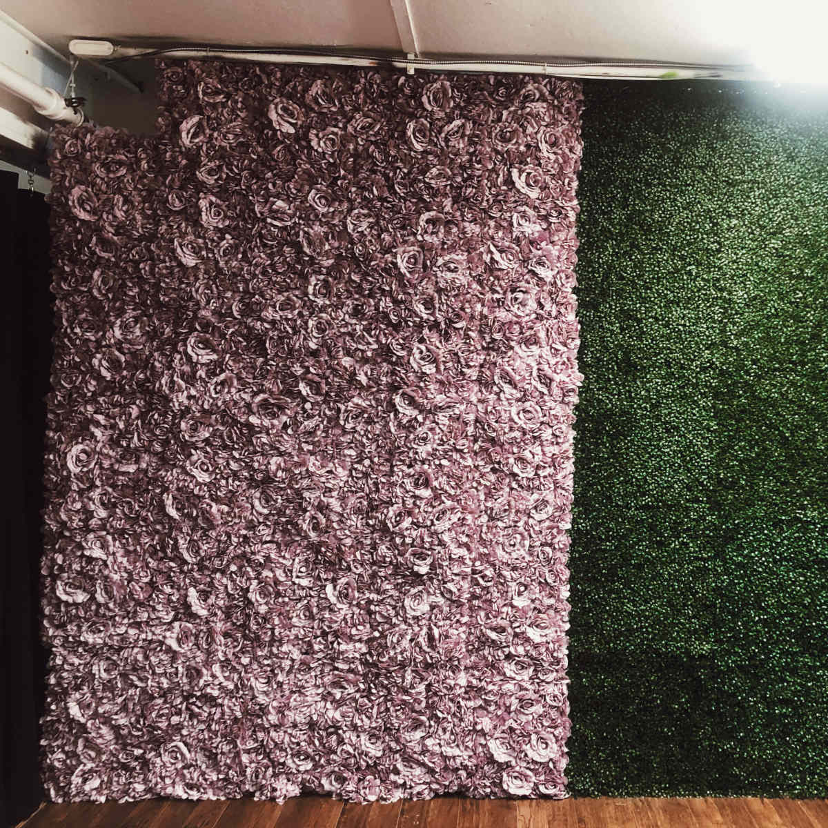 A wall divided into two sections, one covered with purple floral decorations and the other with green artificial grass.