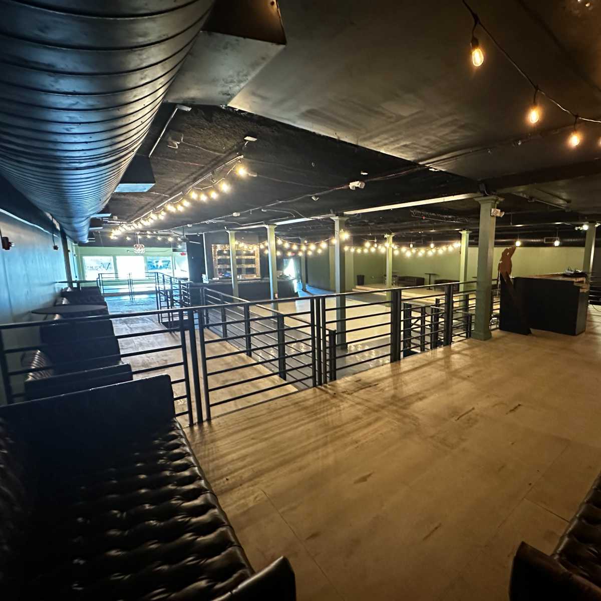 An empty, well-lit indoor venue with string lights and seating areas arranged around a central space.