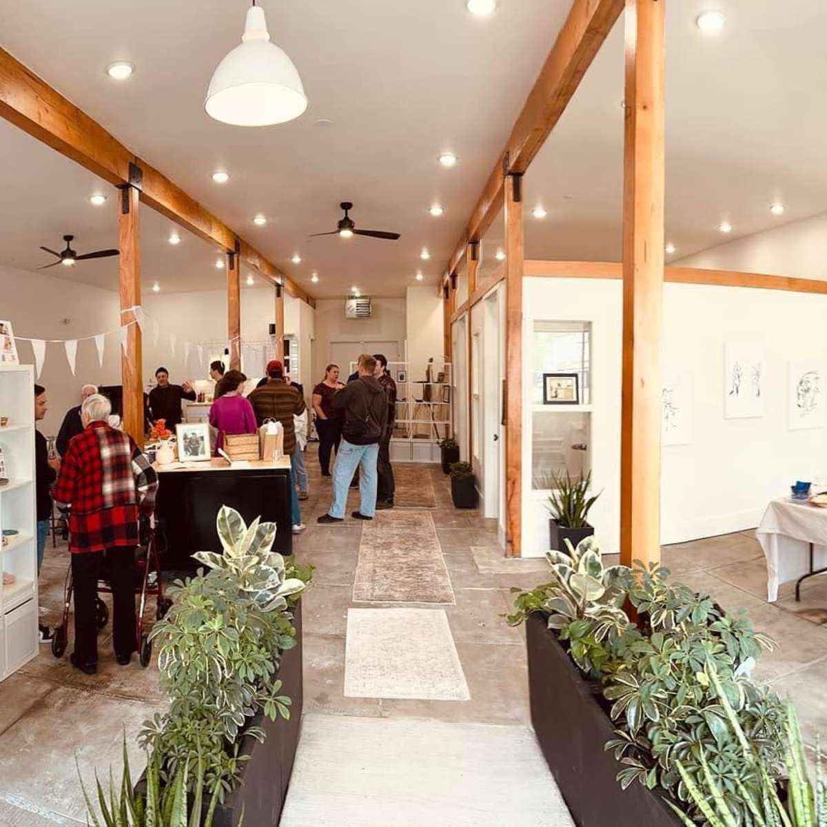 An interior space designed for an event, featuring a gathering of people, decorative 2024 balloons, shelves with items, and refreshments on tables.