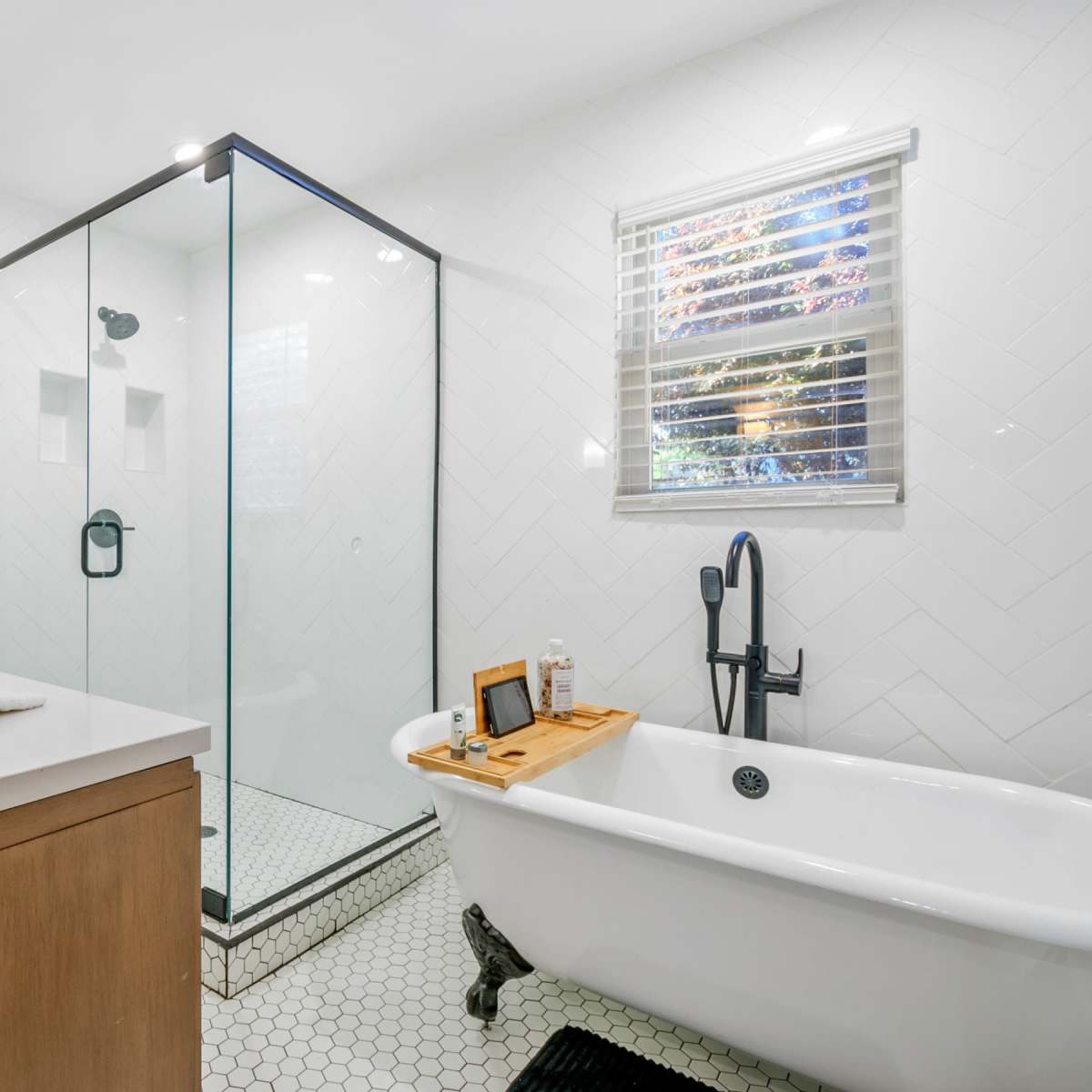 A modern bathroom featuring a glass shower enclosure, a freestanding bathtub with claw feet, and a double sink vanity.