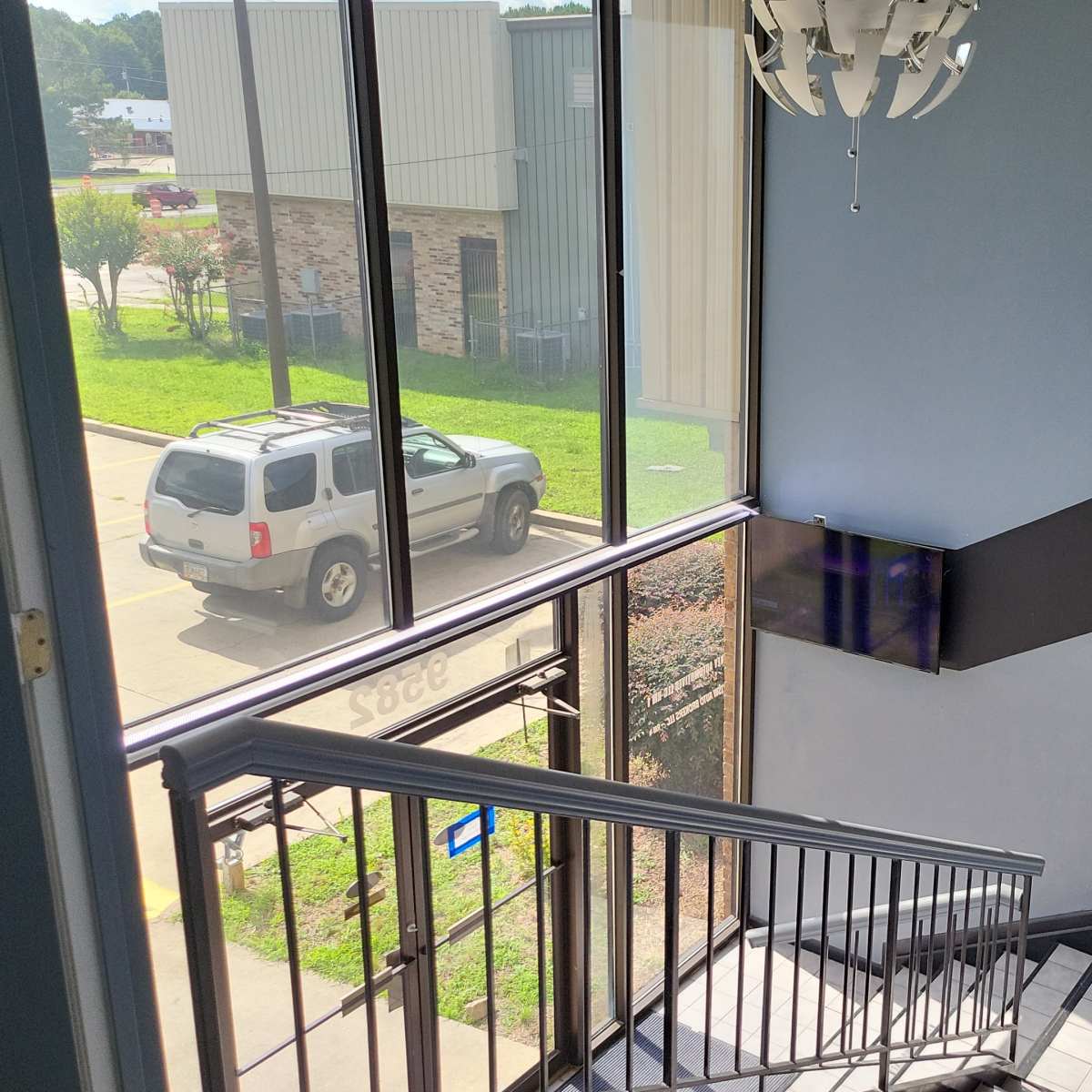 A stairwell with a view of a parked vehicle outside through large windows.