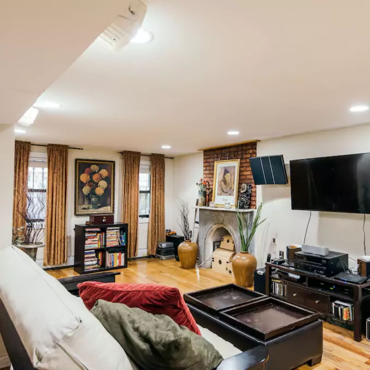 A living room with a television mounted on the wall, a fireplace, wooden flooring, and furniture arranged around a coffee table.