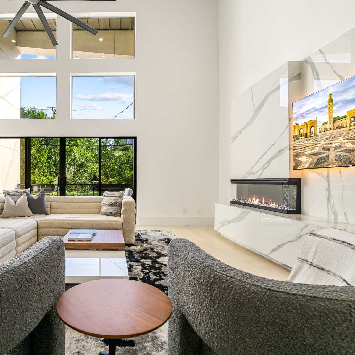 A modern living room with large windows, a sleek fireplace, and contemporary furniture arranged in an open layout.