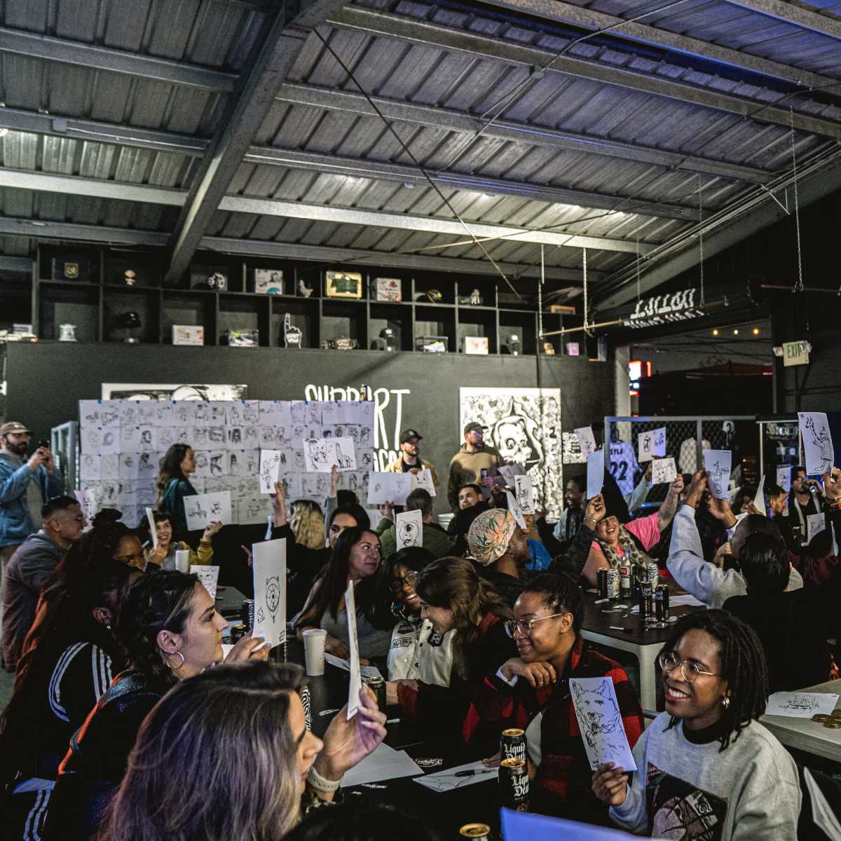 A crowd of people hold up numbered signs in a lively indoor event space.
