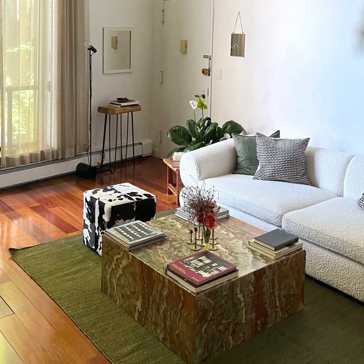 The living room features a white sectional sofa, a large stone coffee table, and a ceiling fan, with natural light streaming through tall curtains.