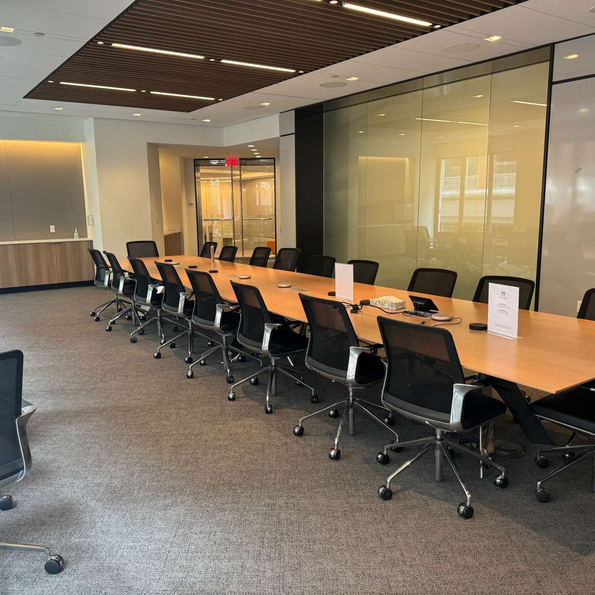 A long conference table with rolling chairs is set up in a well-lit modern meeting room.