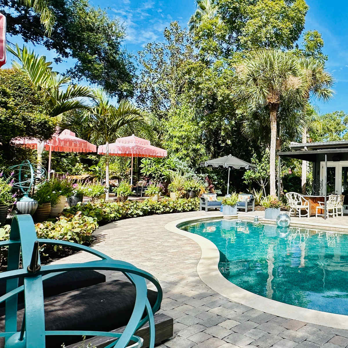 A garden features a swimming pool surrounded by lush greenery and outdoor seating areas.